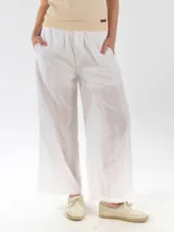 Pantalón ancho color blanco confeccionado en tela broderie con forro interior, de corte recto y tiro medio con cintura elástica.