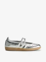 Zapatillas Adidas Samba Jane W de color plateado, con diseño híbrido entre zapatilla y Mary Jane, confeccionadas en piel y material sintético. Presentan tres bandas laterales blancas, tira ajustable con cierre de velcro en el empeine, y suela de goma de tipo caramelo.
