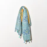 Pashmina rectangular con estampado de flores en tonos celeste, azul y verde, con borde amarillo y flecos en los extremos.