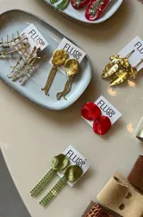 Caravanas colgantes de diseño irregular con base circular texturizada en tono dorado y flecos largos de strass brillantes.