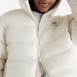 Campera puffer acolchada de color blanco marfil con capucha, cierre frontal completo y bolsillos laterales. Cuenta con el logotipo de New Balance bordado en el pecho.