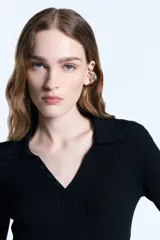 Chomba de punto acanalado color negro, con cuello polo, escote en V con botones y mangas 3/4 con puños de lurex. Presenta un diseño ajustado al cuerpo y un detalle metálico en la espalda.