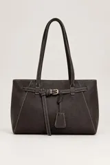 Cartera tipo tote de color marrón oscuro, con diseño estructurado, costuras en contraste y doble asa de hombro. Cuenta con un detalle de tira con hebilla metálica dorada y un colgante decorativo en la parte frontal.