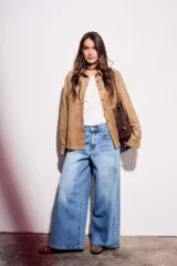 Camisa color marrón de gamuza sintética, de corte recto, con cuello clásico, cierre frontal con botones y mangas largas.