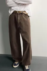 Pantalón barrel fit de mezclilla color verde militar, con efecto lavado, cinco bolsillos, cierre frontal con cremallera y botón, y detalle de pinzas en las rodillas.