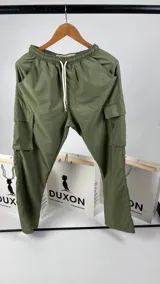 Pantalón cargo verde de nylon, corte holgado con bolsillos laterales y cintura elástica ajustable con cordón.