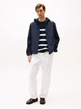 Campera azul marino con capucha, cierre de cremallera, dos bolsillos en la cintura y puños elásticos con botones a presión. Tiene un parche con el logo de Tommy Hilfiger en la manga.