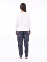 Remera de manga larga color crema con cuello redondo y un estampado central de un ramo de flores rosadas y naranjas en un jarrón azul oscuro.