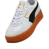Championes urbanos Puma modelo Palermo Platform, color negro con franja lateral blanca y suela de plataforma color caramelo. Presenta detalles en dorado en la lengüeta y el lateral.