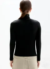 Polera de manga larga en tejido rib negro, con cuello alto ajustado.