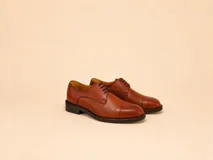 Zapato de vestir tipo oxford de cuero color marrón, con costuras reforzadas en la puntera, cordones al tono y suela de goma negra.
