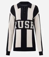 Buzo de punto jacquard con diseño a rayas verticales en blanco y negro. Presenta un corte oversized, cuello polo con cierre frontal de tres botones y estampado frontal con la palabra 'RUSH' en tipografía universitaria.
