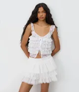 Pollera corta de algodón color blanco, con volados en capas y detalles de encaje floral.