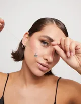 Dije plateado con forma circular y bordes irregulares, con la palabra 'Amor' escrita en cursiva.