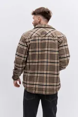 Campera tipo sobrecamisa de franela a cuadros en tonos marrones y beige, con interior forrado en corderito blanco. Presenta cierre frontal, bolsillos en el pecho con solapa y mangas largas con puños abotonados.