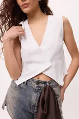 Chaleco blanco de lino y algodón, con escote en V y cierre frontal de botones.