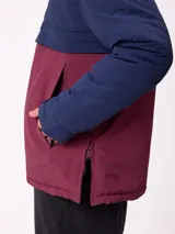 Campera tipo canguro con capucha, diseño color block en azul marino y bordó. Cuenta con cierre frontal parcial, bolsillos laterales y logo de la marca bordado en el pecho.