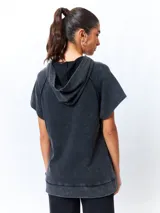 Chaleco negro lavado de algodón con capucha y gran bolsillo central. De corte oversized, holgado, suave y cómodo.