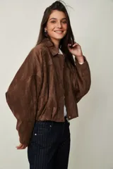 Campera de gamuza marrón, de corte oversize con hombros caídos, cuello camisero, cierre frontal de cremallera y puños y dobladillo elásticos.