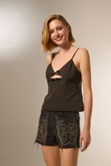 Musculosa de color blanco con breteles finos, escote en V y detalle de aberturas frontales con lazos decorativos.