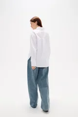 Camisa de algodón blanca con estampado de corazones formados por pequeños cristales de strass. Presenta cuello clásico, cierre frontal con botones, bolsillo en el pecho y mangas largas con puños abotonados.