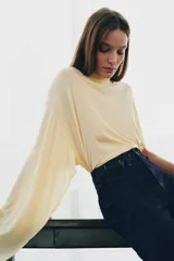 Jeans de tiro alto con corte flare y ajuste slim. Presenta trabillas en la cintura, bolsillos delanteros con detalle de botones metálicos y raya planchada a lo largo de las piernas. Cierre frontal con cremallera y botón.