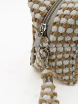 Necessaire de mano con diseño texturizado de puntos en relieve, combinando colores beige y blanco. Cuenta con cierre superior y una correa de muñeca a juego.