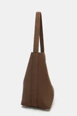 Bolso de hombro tipo saca, de diseño minimalista y estructura flexible, con asa única y cierre mediante clip metálico.