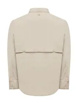 Camisa de manga larga color crema, diseñada para actividades al aire libre. Presenta cuello clásico, cierre frontal con botones, bolsillos en el pecho y ventilación en la espalda. Confeccionada en tela técnica ultraligera de secado rápido con protección UV.