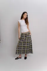 Falda midi de popelina de algodón negra con estampado geométrico de cuadros en tonos blancos, amarillos y rosados, con bolsillos laterales.