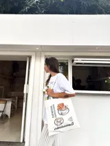 Bolso tote color beige con estampado de tazas de café y la palabra "croissants".