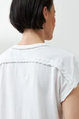 Remera color durazno con cuello en V y detalle de trenza en el escote.