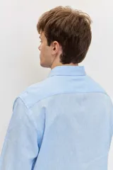 Camisa celeste de manga larga con cuello camisero abotonado y cierre frontal con botones.