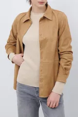Camisa de estilo casual confeccionada en material tipo gamuza color marrón, con cuello clásico, cierre frontal con botones y costuras a la vista en tono contrastante.
