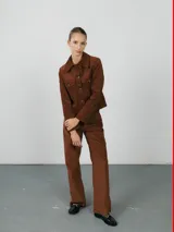 Pantalón de corte recto y tiro medio, confeccionado en pana color marrón, con bolsillos laterales y cierre frontal.