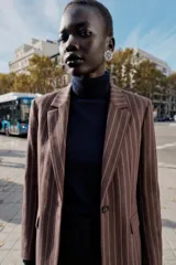 Blazer de corte sastrero con diseño de rayas verticales, cuello con solapas, cierre frontal con un botón y bolsillos laterales con solapa.