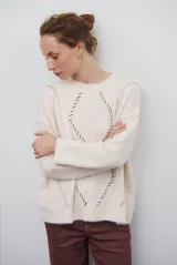 Buzo de punto color beige con diseño de trenzas y costuras decorativas en contraste que forman rombos. Presenta cuello redondo, mangas largas y puños acanalados.