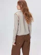 Polera de cuello alto confeccionada en tela rib color blanco, con mangas largas y hombreras. Presenta pespuntes en contraste en las terminaciones del cuello, hombros y puños.