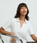 Blusa polo marrón de manga corta en tejido de algodón texturizado, con cuello tipo polo y abertura frontal en V.