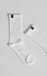 Medias blancas de caña alta, confeccionadas en mezcla de algodón y spandex, con detalle de etiqueta negra con logo de tijeritas en el borde superior.