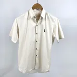 Camisa de manga corta color beige jaspeada con cuello común y cierre con botones.