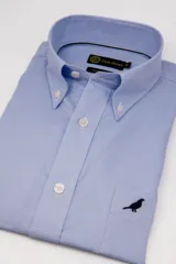 Camisa de vestir Club House color celeste con micromotivo a cuadros, cuello button-down, botones blancos, bolsillo ojal en el pecho con bordado de un pájaro en negro y mangas largas.