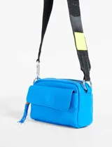 Bandolera mini color azul eléctrico, con bolsillo frontal con solapa y correa de hombro ancha regulable en color negro con detalle amarillo.
