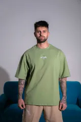 Remera oversize de algodón elastizado color verde militar, con cuello redondo, mangas cortas y diseño gráfico bordado en el pecho.