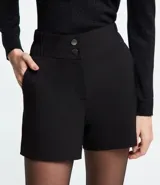 Bermuda roja de poliéster con cintura elástica, bolsillos laterales y cierre con cremallera y botones.