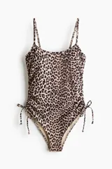 Malla enteriza de corte alto con estampado animal print de leopardo, tirantes finos y laterales fruncidos con cordones ajustables.