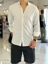 Camisa de lino color beige, de manga larga con puños arremangados y cuello mao. Cuenta con cierre frontal de botones y diseño clásico.