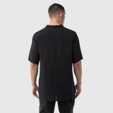 Camisa de manga corta confeccionada en viscosa, con cuello solapa y cierre frontal de botones. Presenta un estampado de cuadros vichy en tonos oscuros.