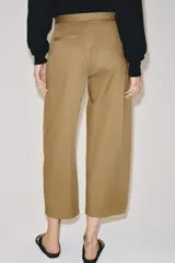 Pantalón de tiro medio confeccionado en mezcla de lyocell, con diseño de pliegues delanteros superpuestos y bolsillos laterales ocultos en costura.
