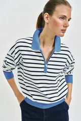 Sweater de punto con diseño a rayas horizontales en blanco y negro, manga larga, cuello polo en color celeste y cierre frontal parcial con cremallera.